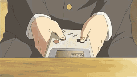 a person is holding a video game controller in their hands while sitting at a table .