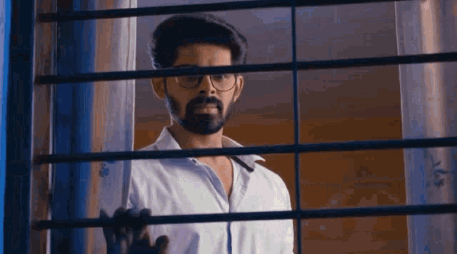 a man with a beard is looking out of a window .