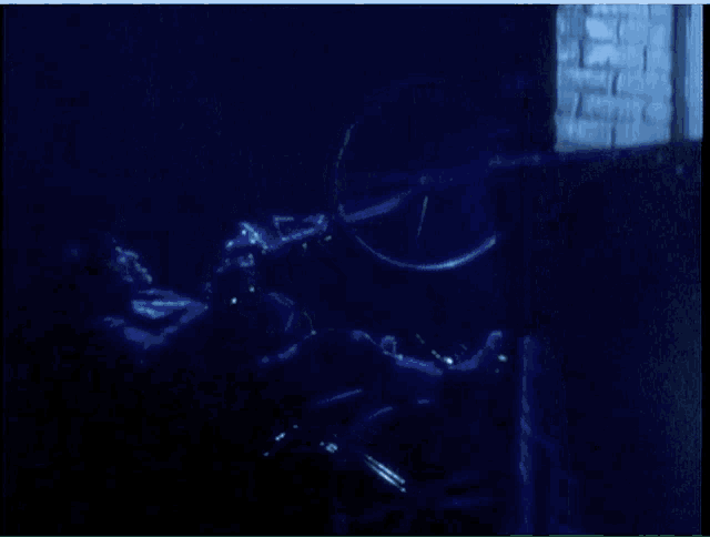 a person is sitting in a dark room with a bicycle wheel in the background