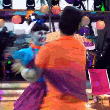 a man in an orange shirt holds a woman in a purple dress