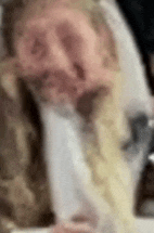 a blurry picture of a man with a beard sitting at a table eating noodles .