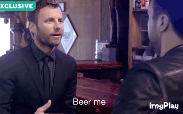 a man in a suit and tie is talking to another man in a leather jacket and the words beer me are on the screen