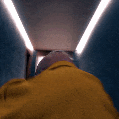 a man in a yellow jacket looks down a hallway