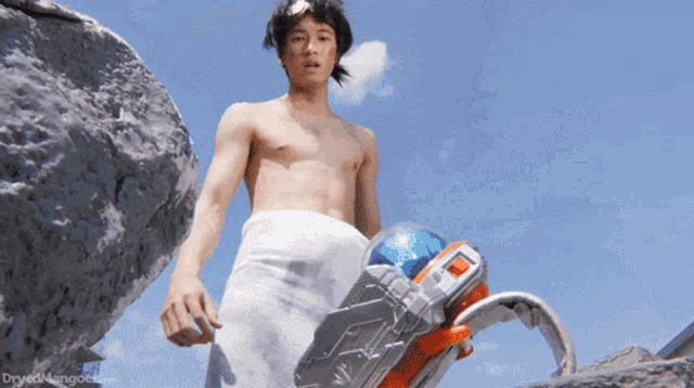 a shirtless man with a towel around his waist is holding a toy