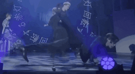 a group of people are dancing on a stage in front of a blue background .