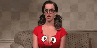 a woman is sitting on a couch wearing glasses and a red shirt with an owl on it .