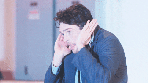 a man covering his ears with his hands while looking down