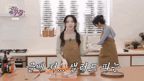 two women in aprons are cooking in a kitchen with korean writing on the counter