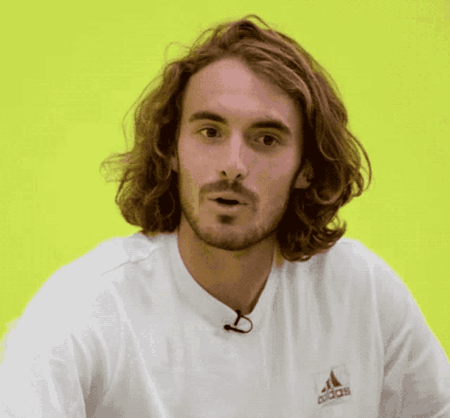 a man with long hair is wearing a white adidas shirt