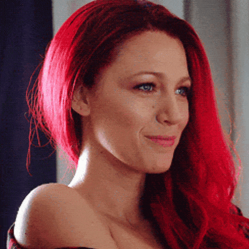 a woman with red hair is smiling and looking down
