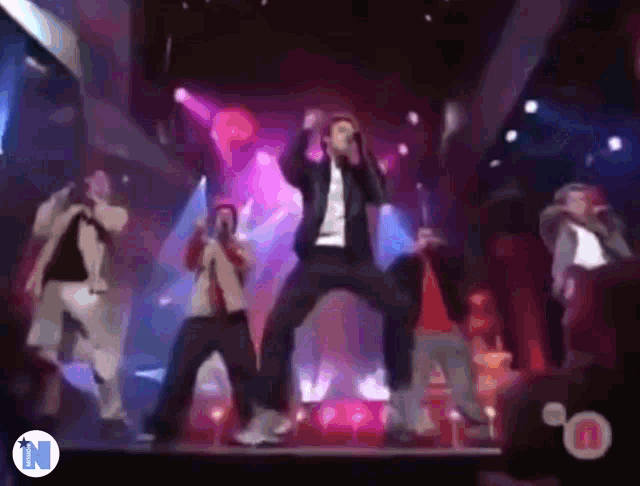 a group of men are singing and dancing on a stage