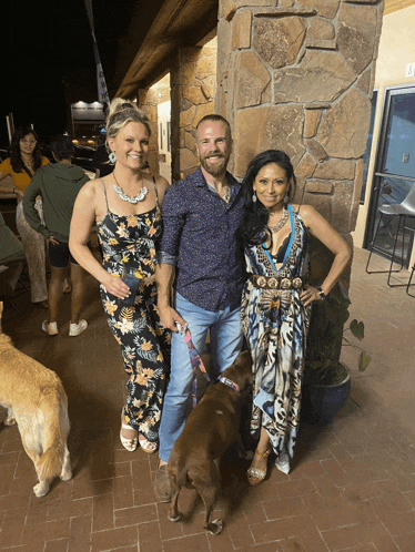 a man and two women standing next to a brown dog