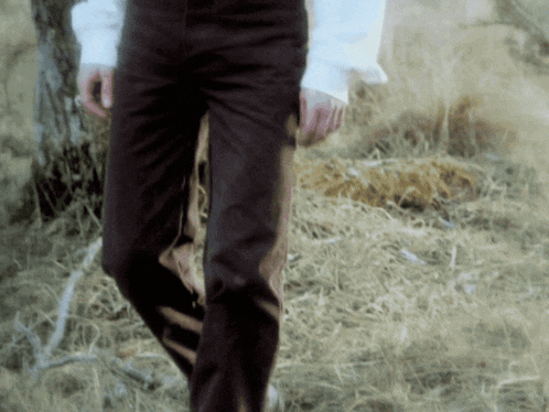 a man in brown pants is walking through a field