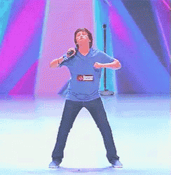 a boy in a blue shirt with a name tag that says ' jackson ' on it is singing into a microphone