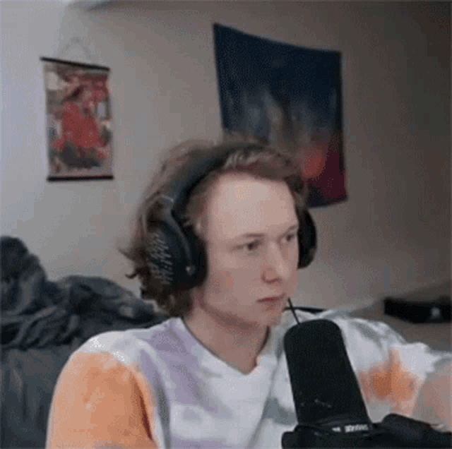 a man wearing headphones is sitting in front of a microphone .