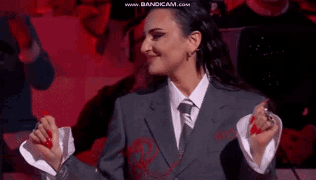 a woman in a suit and tie is smiling in front of a crowd ..