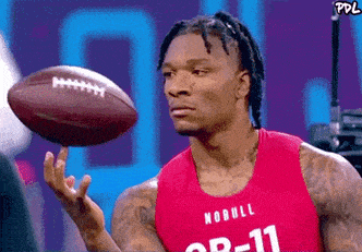 a man is holding a football in his hand and wearing a nobull jersey .