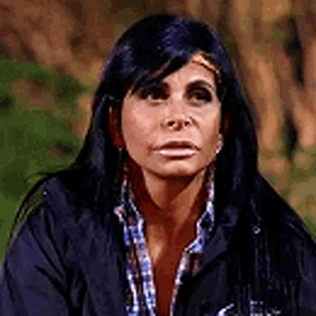a woman with long black hair is wearing a black jacket and plaid shirt .