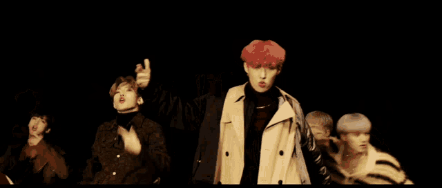 a man with red hair is standing in a dark room with two other men