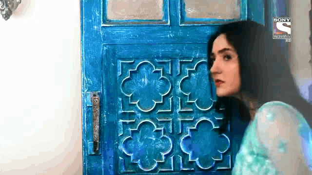 a woman is standing in front of a blue door that says sony