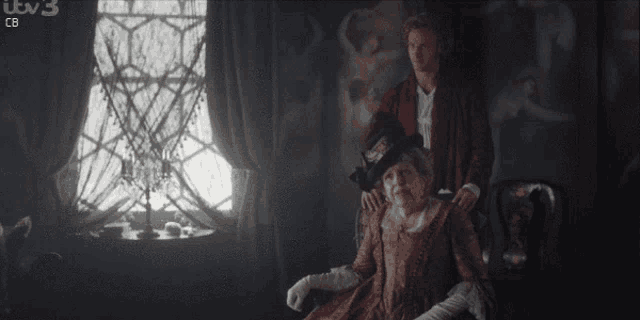 a man standing next to a woman in a chair with itv 3 cb written on the bottom