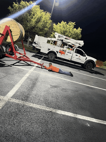 a man is laying on the ground in front of a utility truck that says utility on it