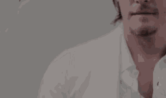 a man wearing sunglasses and a white shirt is looking down .