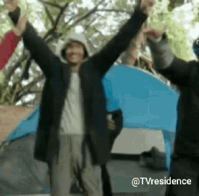 a group of people standing in front of a tent with their hands in the air .