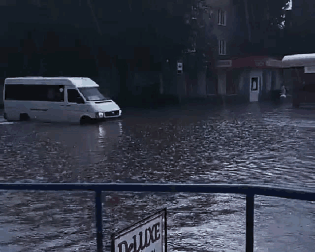 a flooded street with a sign that says deluxe in the foreground