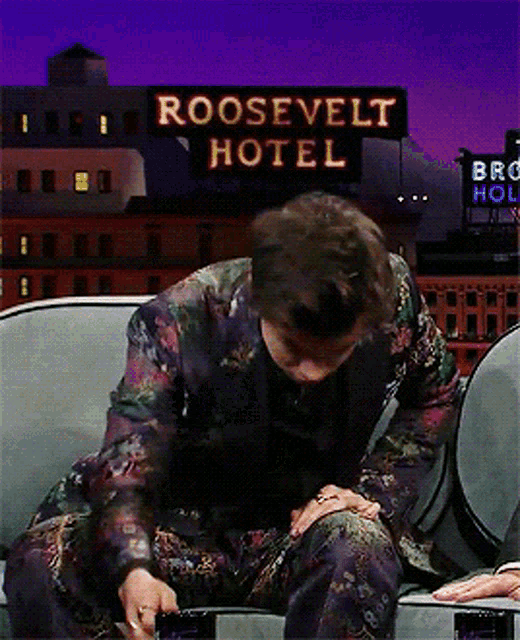 a man is sitting in front of a roosevelt hotel sign