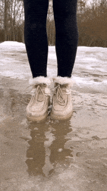 a person standing in a puddle of water wearing a pair of boots