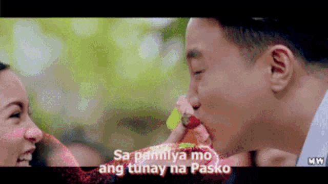 a man is feeding a woman a gummy bear and the words sa pamilya mo ang tunay na pasko are on the bottom