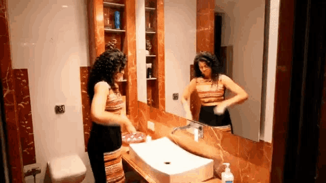 a woman is standing in front of a bathroom sink