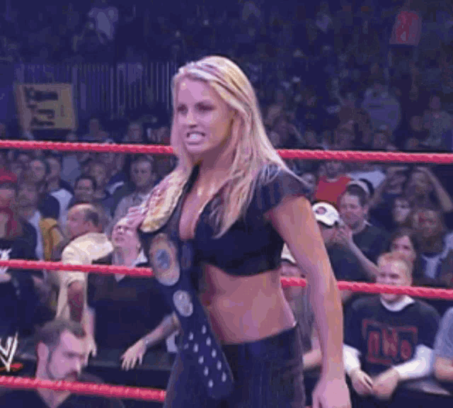 a woman is standing in a wrestling ring with a crowd behind her and a sign that says ring