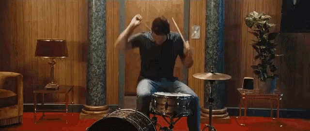 a man is playing drums in a room with columns