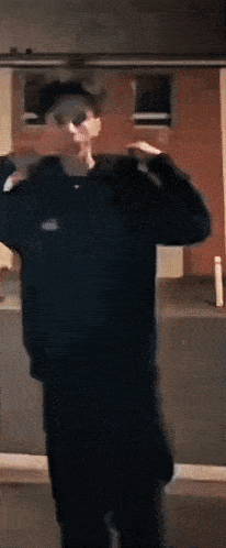 a man in a black hoodie stands in front of a mirror
