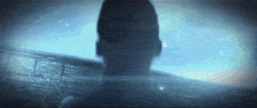 a man 's head is visible in a dark room with a blue background