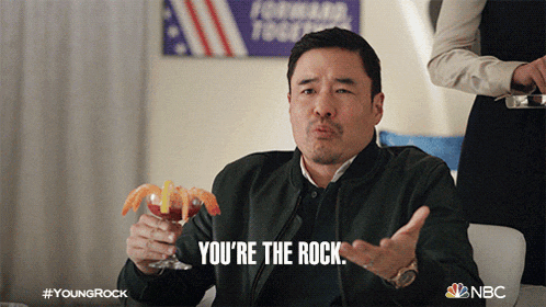a man holding a martini says you 're the rock in front of an american flag