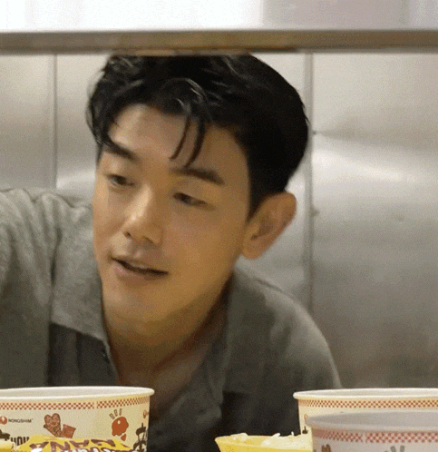 a man in a grey shirt looks at a bowl of food that says ' chicken ' on it
