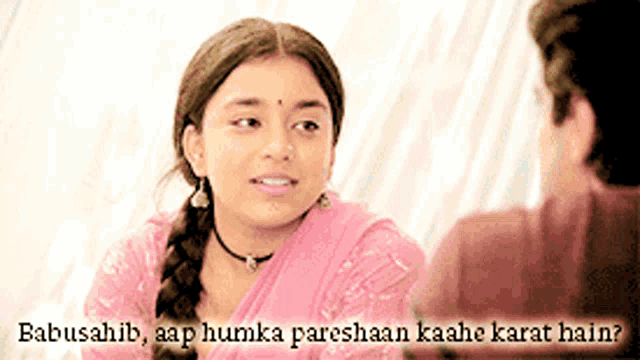 a woman in a pink sari is talking to a man in a red shirt