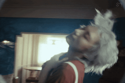 a woman with white hair is looking at herself in a mirror with the letter u on it