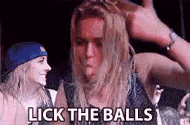 a man with long blonde hair is standing in front of a crowd of people and licking the balls .