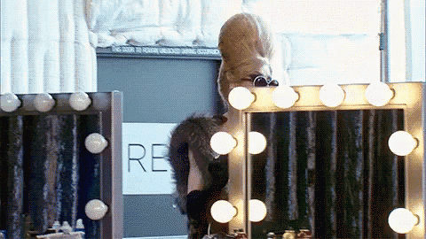 a woman is looking at herself in a mirror in front of a sign that says ' re '