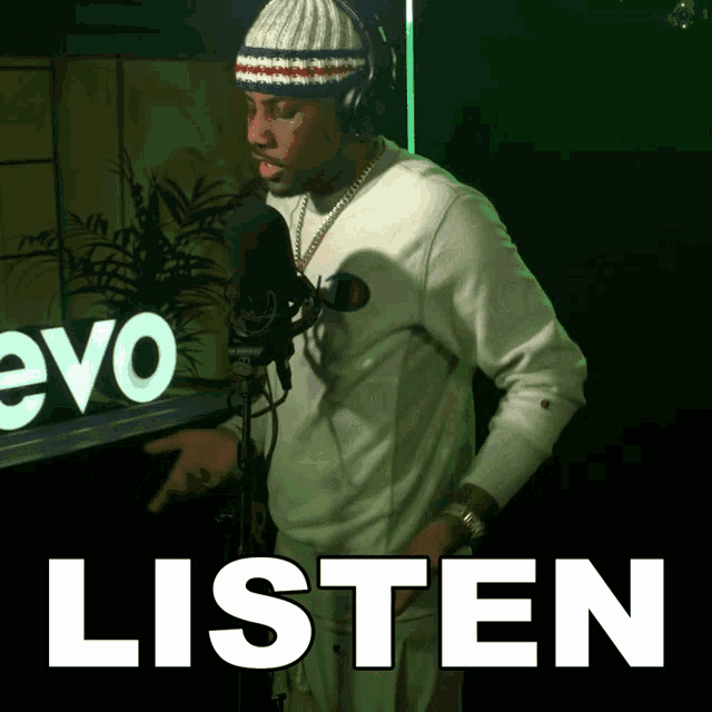a man stands in front of a microphone with the word listen above him