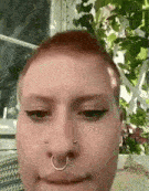 a close up of a woman 's face with a nose ring and a piercing .