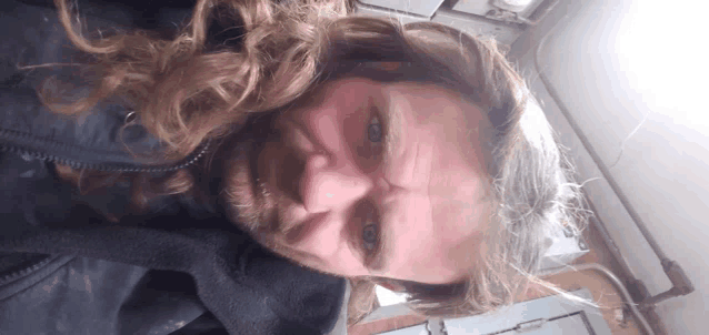 a man with long hair and a beard is looking down