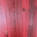a close up of a red wooden surface with a grain .