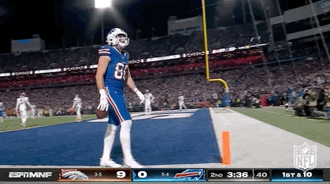 a football player in a buffalo bills uniform is standing on the field with a ball .
