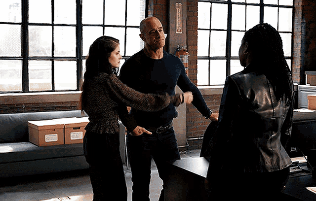 a man and two women are shaking hands in a room with boxes on the floor