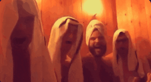 a group of men are standing in a room with towels on their heads
